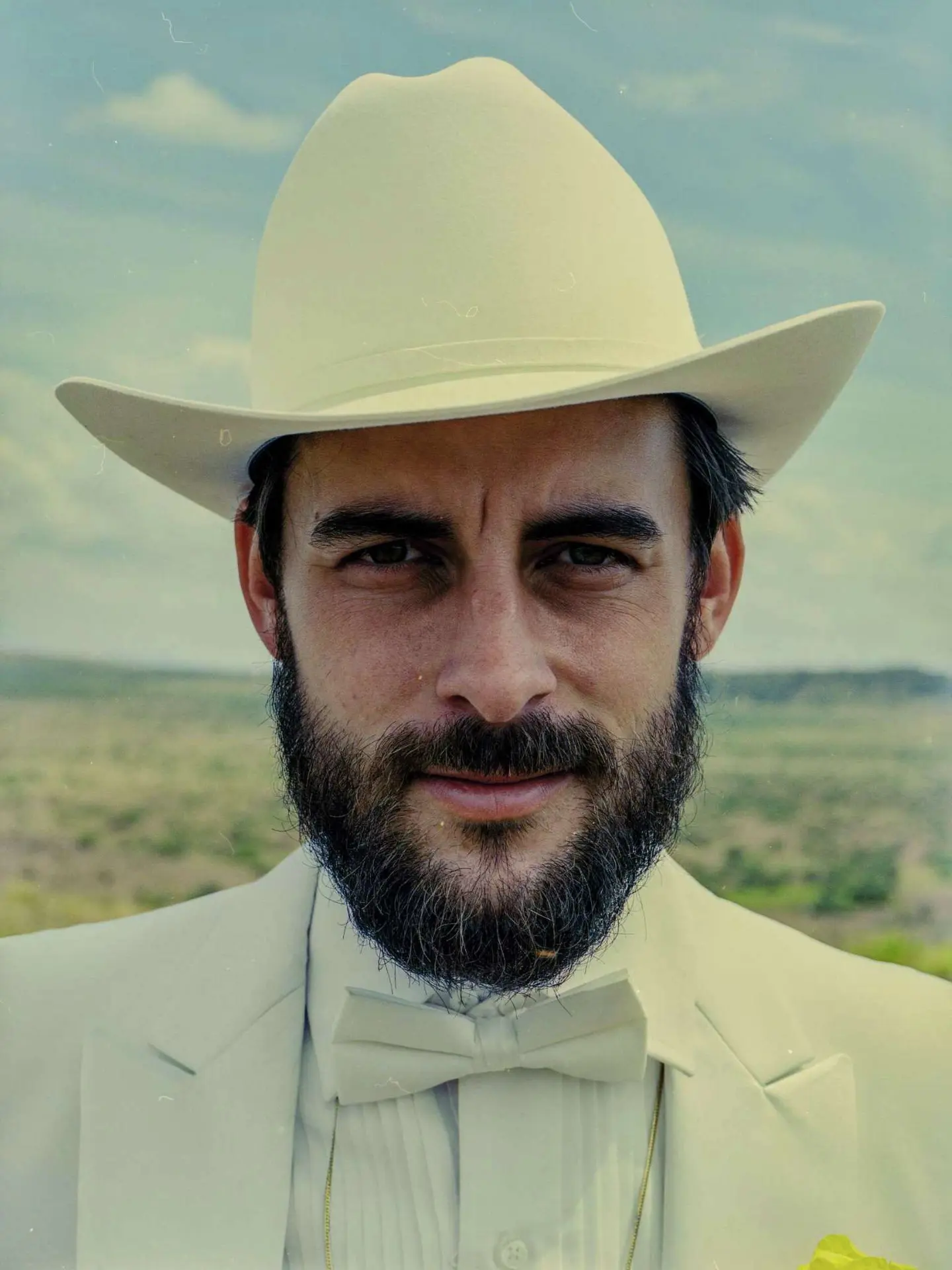 Portrait of Robert Ellis wearing a white cowboy hat and suit.