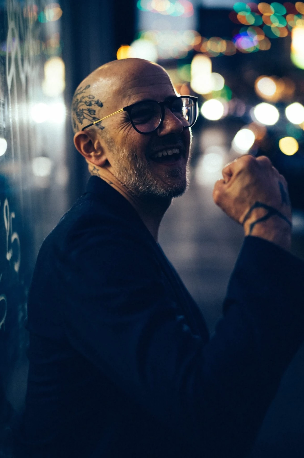 Tyler Barber laughing on a city street at night, city lights blurred behind him.