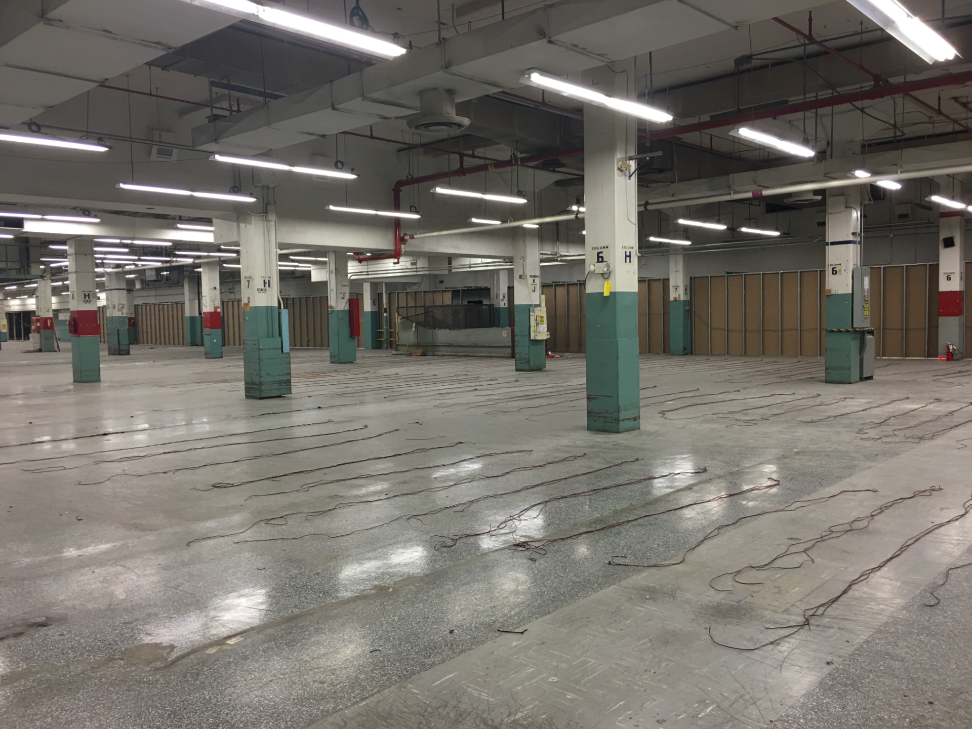 The empty main work floor of the former Barbara Jordan Post Office, its lettered and numbered columns painted teal and red, before any event programming.
