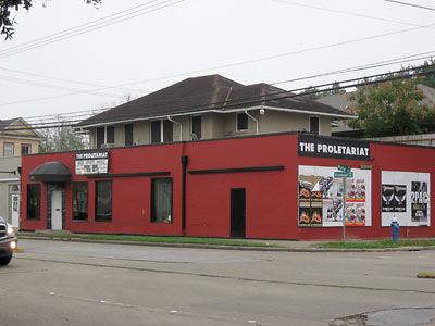 Red-painted exterior of The Proletariat on Richmond Avenue, poster-mural signage beside the entrance.