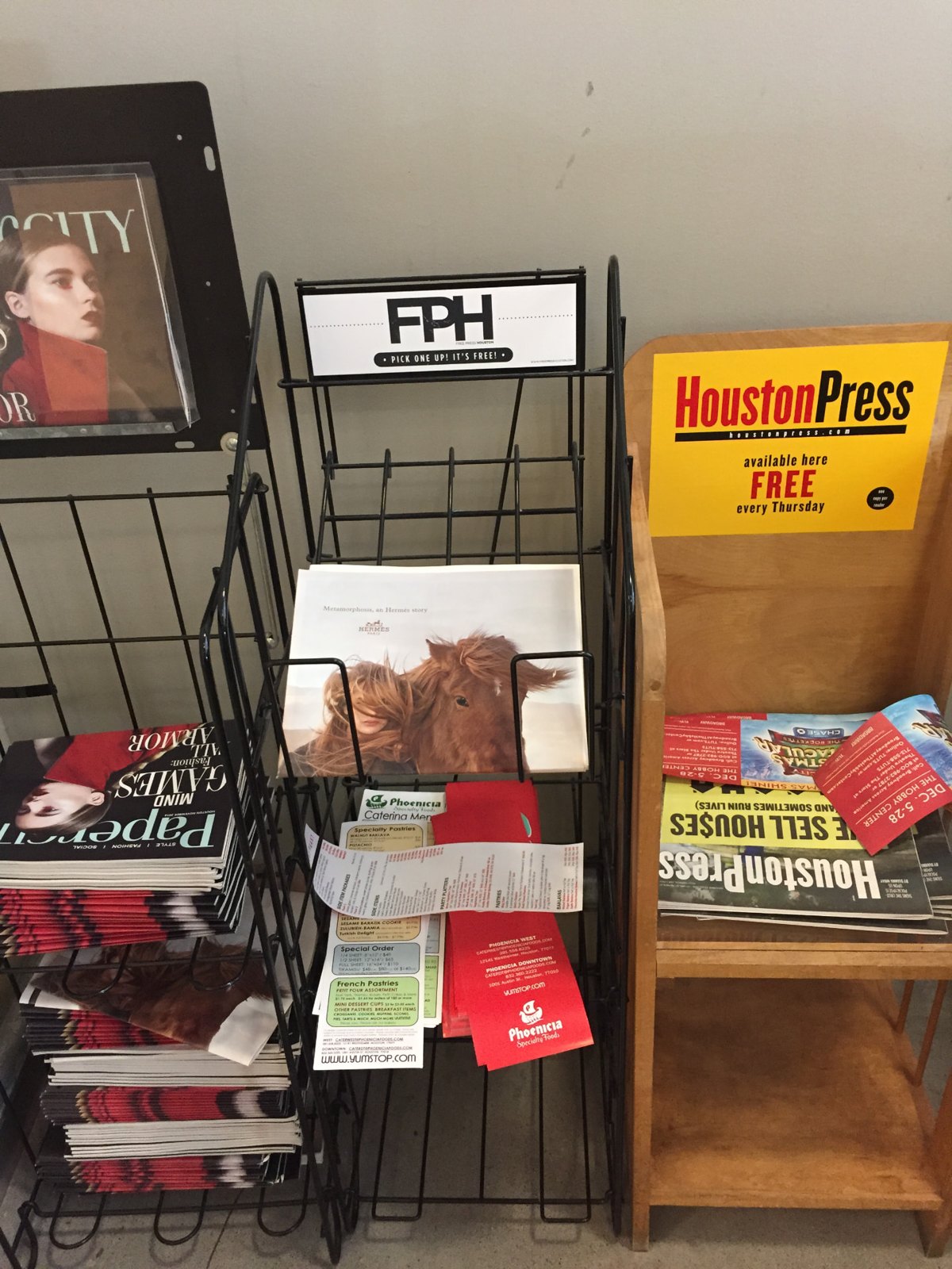 Wire street rack headed FPH / PICK ONE UP! IT'S FREE! beside a Houston Press rack and a stack of magazines; date and photographer not established.